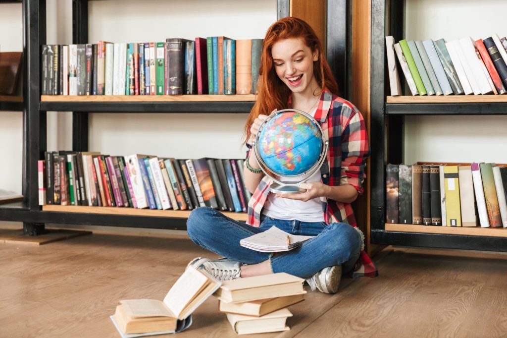 Excited teenage girl holding globe