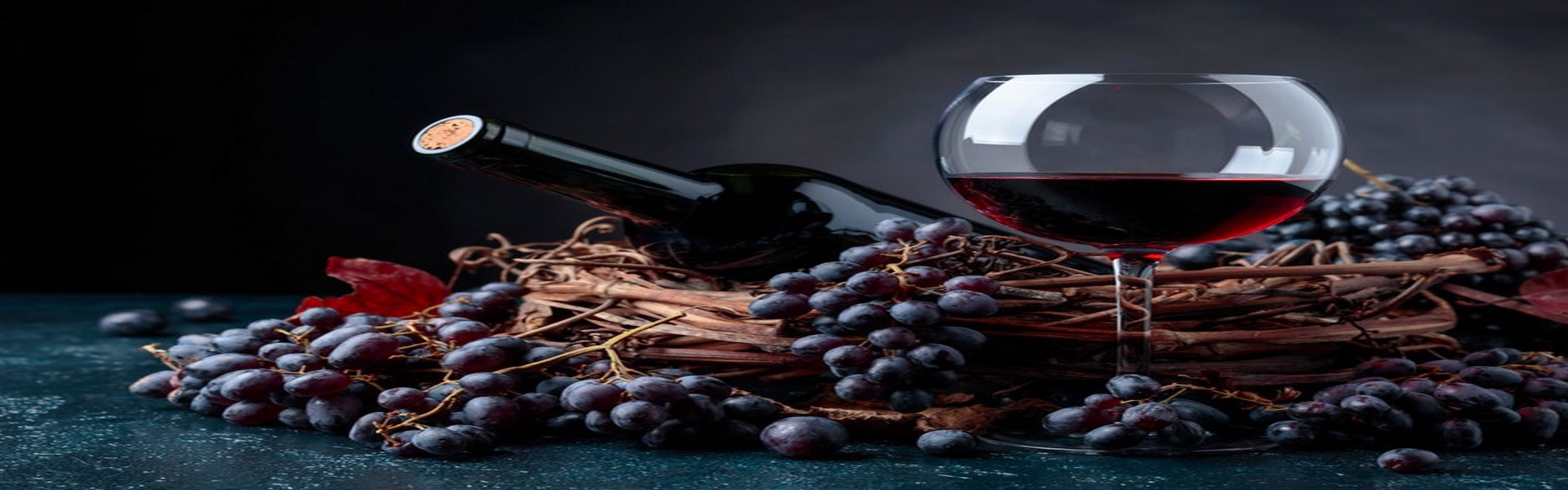 Bottle and glass of red wine with grapes.